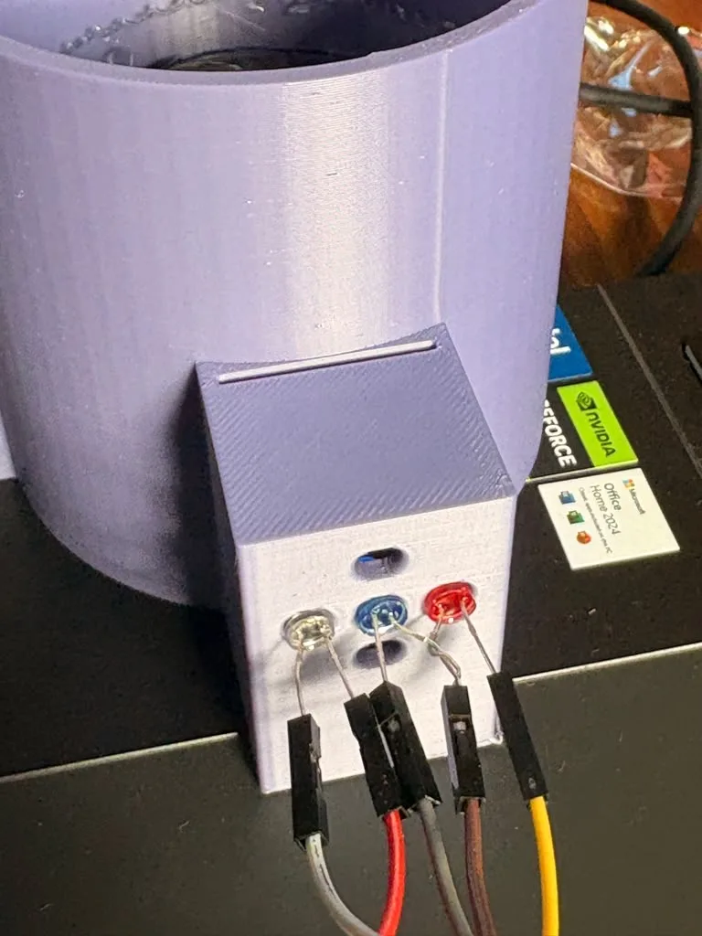 Close-up of the purple LED box on the side of the chamber: a white, a blue and a red 5 mm LED in a row with jumper wires on their legs, two empty holes above and below the blue LED, and a thin slot on top